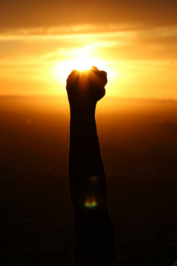 Poing levé devant un coucher de soleil